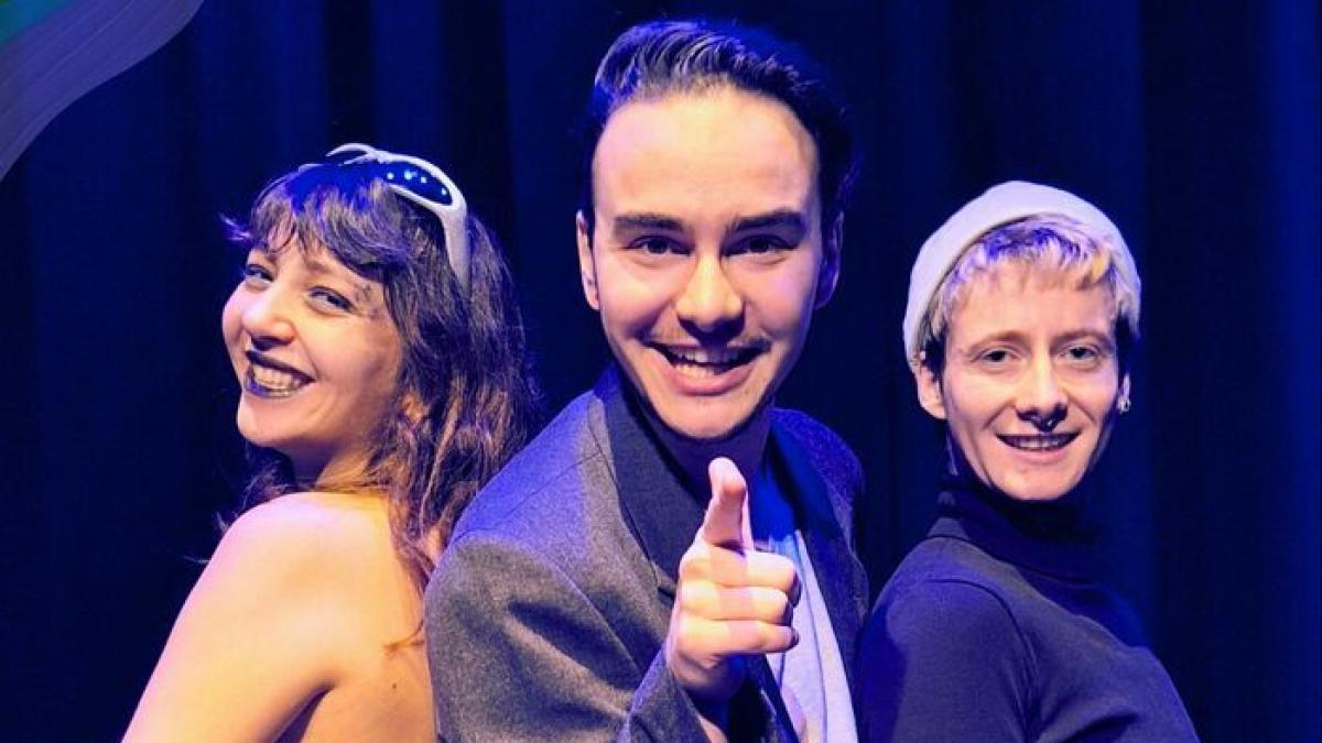 Les invités du plateau télé de l'émission Le monde vous appartient spéciale LGBT Il s'agit d'une photo des personnes présentes sur le plateau télé : le présentateur est au milieu, tandis que Aurel, le gagnant de top chef est à sa droite et Otto Mat, la rappeuse à sa gauche. Ils regardent tous en direction de la caméra.